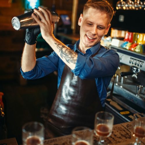 Bartender works with shaker at the bar counter